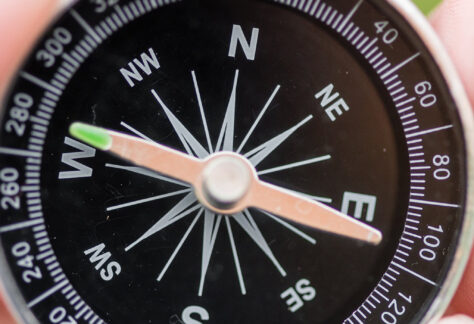 Nahaufnahme eines schwarzen Kompasses in der Hand zeigt Orientierung und Richtung - Impulsvortrag Auf Kurs bleiben professionelle Selbstreflexion Beratungsalltag