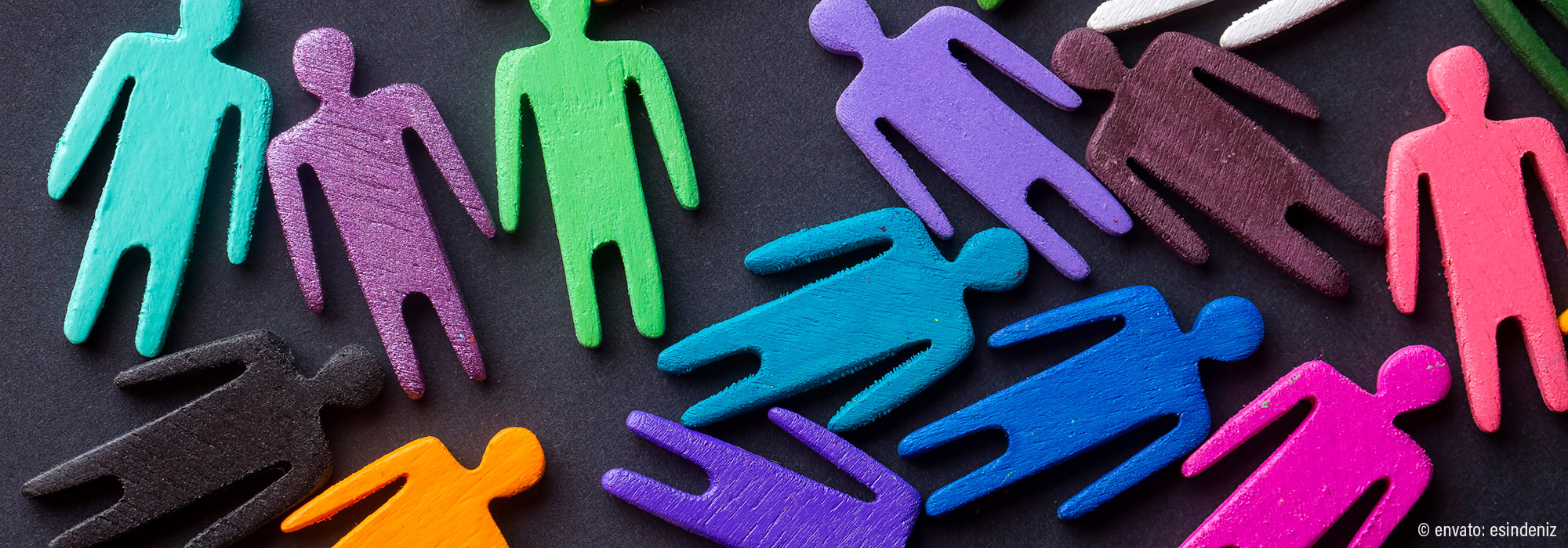 Bunte Holzfiguren in Türkis Lila Grün Blau Orange Pink auf schwarzem Hintergrund symbolisieren Vielfalt - Autismus Basis Plus Intensivwoche Fortbildung Lebenshilfe Alfeld