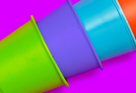 Ineinander gestapelte Becher in Grün Lila Türkis Rot vor pinkfarbenem Hintergrund - Fachmodul Autismus kommt selten allein Begleitdiagnosen Lebenshilfe