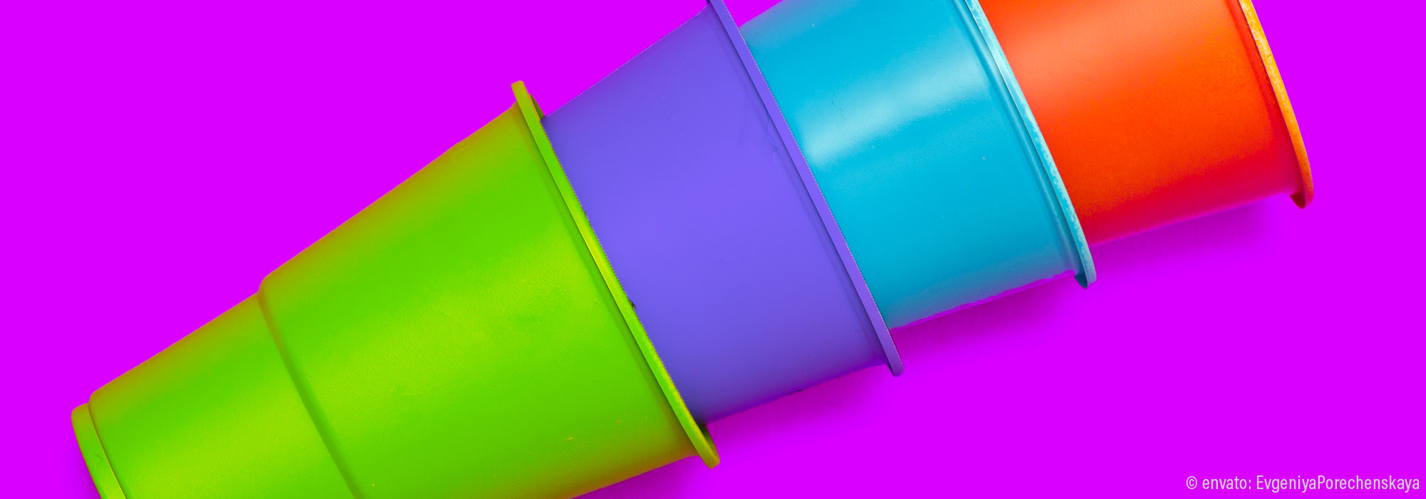 Ineinander gestapelte Becher in Grün Lila Türkis Rot vor pinkfarbenem Hintergrund - Fachmodul Autismus kommt selten allein Begleitdiagnosen Lebenshilfe