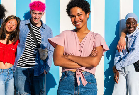 Diverse Gruppe junger Menschen in bunter Kleidung vor blau-weißer Wand - Fortbildungsreihe Schulbegleitung Lebenshilfe Alfeld