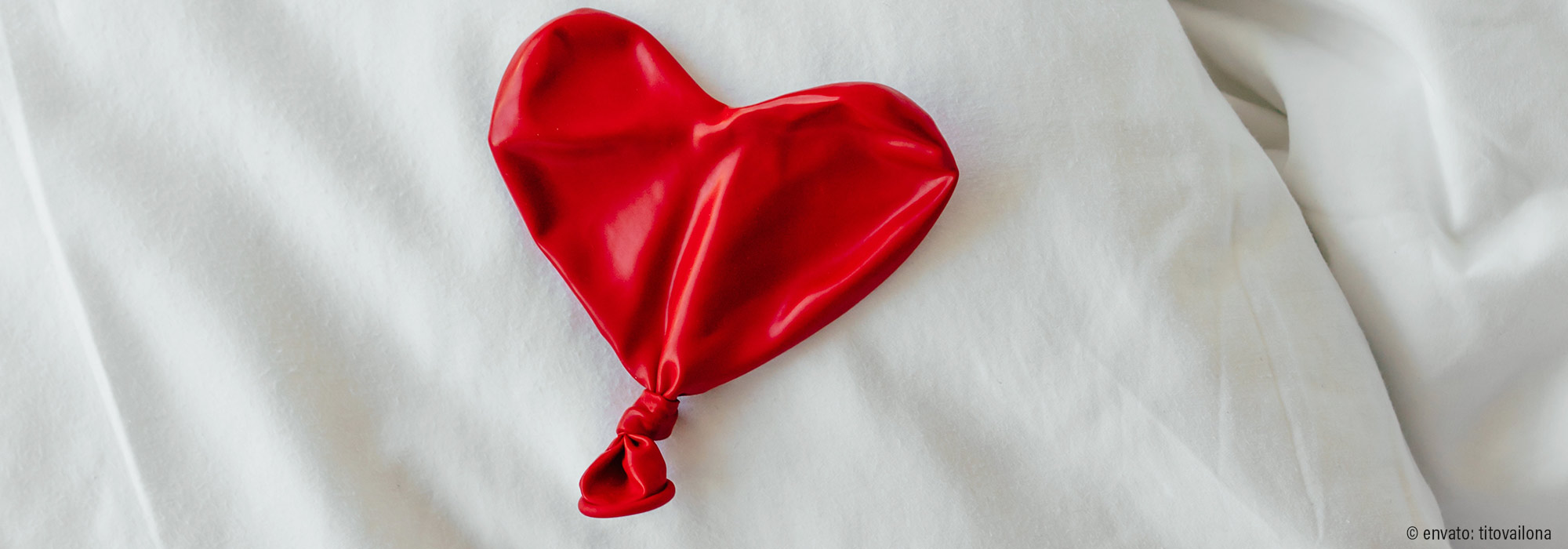 Zusammengefallener roter Luftballon in Herzform auf weißem Untergrund - Fachmodul Märchen der Gefühllosigkeit Emotionen soziale Beziehungen Spektrum