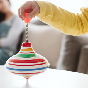 Kind in gelber Kleidung spielt mit buntem Kreisel als Selbstregulation - Impulsvortrag Stimming Rückzug Regulation Autismus Lebenshilfe Alfeld