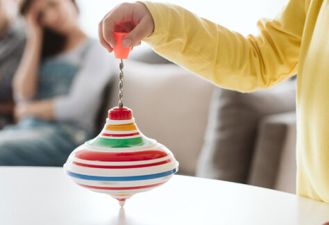 Kind in gelber Kleidung spielt mit buntem Kreisel als Selbstregulation - Impulsvortrag Stimming Rückzug Regulation Autismus Lebenshilfe Alfeld