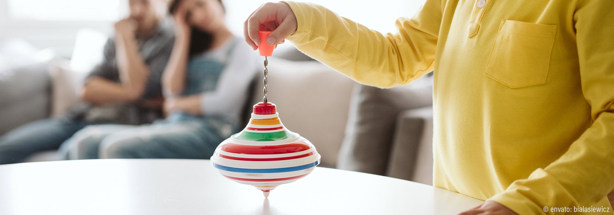 Kind in gelber Kleidung spielt mit buntem Kreisel als Selbstregulation - Impulsvortrag Stimming Rückzug Regulation Autismus Lebenshilfe Alfeld